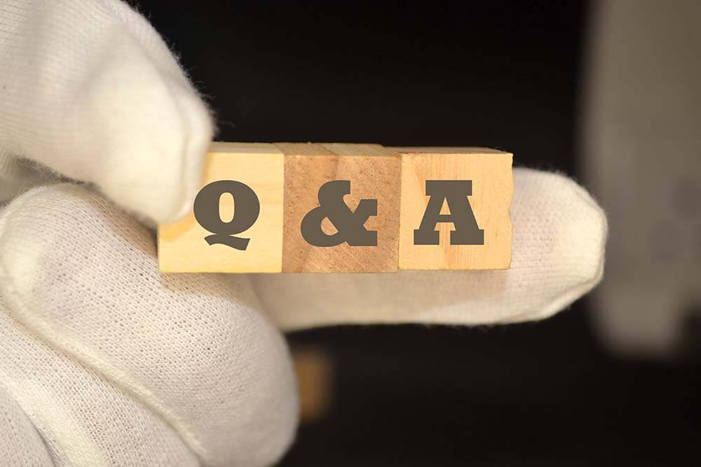 Рука держит деревянные блоки Q&A представляя исчерпывающие вопросы покупателей недвижимости и экспертные